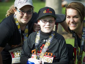 Jonathan Pitre, centre, with his sister Noemy and mother Tina, pose after finishing the 5K race part of Tamarack Ottawa Race Weekend Saturday May 28, 2016.