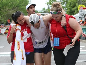 Canadian Matt Vierula is helped by medical staff after crossing the finish line in the half-marathon during Tamarack Ottawa Race Weekend on Sunday, May 29, 2016.