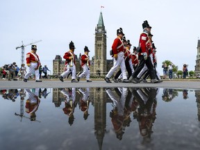 Members of 100th Foot joined by members from Thunder Bay and Winnipeg who acted out the roles of Regiment de Meuron and Regiment de Watteville march in front of the Parliament building as the tourists looks on at Parliament Hill on Saturday, May 21, 2016.