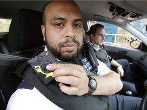 LONDON - MAY 6:  Constable Yasa Amerat (left) and Constable Craig Pearson pictured in their police car wearing body-worn video (BWV) cameras, ahead of a year-long pilot scheme by the Metropolitan police, at Kentish Town on May 6, 2014 in London, England. Officers with the Metropolitan Police will be begin wearing tiny cameras on their uniform, designed to capture evidence at scenes of crime and help support prosecution cases. The trial, thought to be the largest in the world, will see a total of 500 cameras distributed to 10 London boroughs.