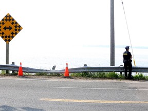 OPP Const. Christine Quenneville keeps watch over the scene on Highway 33 just west of Kingston on Friday where a car went off the road and into Lake Ontario.