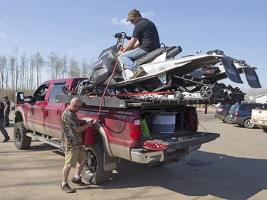 Robert Parker, left and Matt Jones siphon from two skidoos for their truck at a rest stop near Fort McMurray, Alta., on Wednesday, May 4, 2016. A wildfire has put all of Fort McMurray under a mandatory evacuation order which means that about 70,000 people who live in Fort McMurray are being told to flee the city.