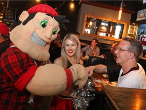 Ron Godwin (R) fist pumps Big Joe (L) as cheerleader Sydney looks on at the CFL Draft party held by the Ottawa Redblacks at Jack Astor's restaurant in Ottawa, May 10, 2016.  Photo by Jean Levac
