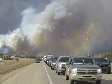 Smoke fills the air as people drive on a road in Fort McMurray, Alberta on Tuesday May 3, 2016. Raging forest fires whipped up by shifting winds sliced through the middle of the remote oilsands hub city of Fort McMurray Tuesday, sending tens of thousands fleeing in both directions and prompting the evacuation of the entire city.