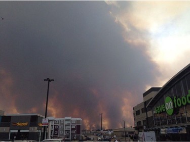 Smoke fills the air near a parking lot in Fort McMurray, Alberta on Tuesday May 3, 2016 in this image provide by radio station CAOS91.1. At least half of the city of Fort McMurray in northern Alberta was under an evacuation notice Tuesday as a wildfire whipped by winds engulfed homes and sent ash raining down on residents.