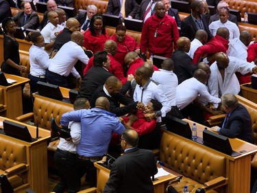 Economic Freedom Fighters (EFF, in red) party members of parliament are physically removed from the South African parliament after repeatedly ignoring the instructions of the Speaker, on May 17, 2016, in Cape Town. A brutal fistfight broke out in the South African parliament on May 17 as security guards ejected opposition lawmakers in an ugly fracas that underlined heightened political tensions over Jacob Zuma's presidency.