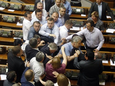 Deputies of the All-Ukrainian Union "Svoboda" party attack the head of the Communist parliamentary faction Petro Symonenko (C) as they attempt to remove him from the hall during a Ukrainian parliament sitting in Kiev on July 23, 2014. Symonenko said in an interview with Russian media that the authorities in Ukraine had killed many thousands of Ukrainians in eastern Ukraine, where they are fighting pro-Russian rebels, and is profiting from the sale of their organs.