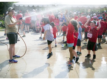 Young runners get some relief from the heat under a hose Laura Tobin was spraying after the 2K race.
