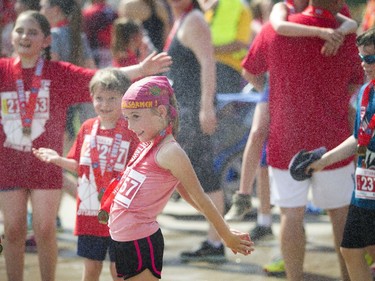 Young runners cool off under a hose after the 2K race.