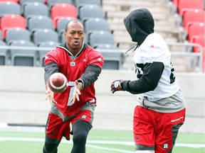 #1 Henry Burris of the Ottawa Redblacks makes the handoff to #29 William Powell (R) during practice at TD Place in Ottawa, June 12, 2016.
