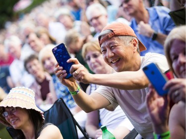 A fan in the crowd takes a photo as Sarah McLachlan performs in Confederation Park.