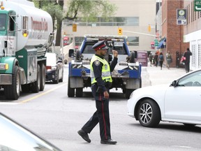 A police officer directs traffic on Waller St. during the afternoon after a sink hole occurred on Rideau St., June 08, 2016.