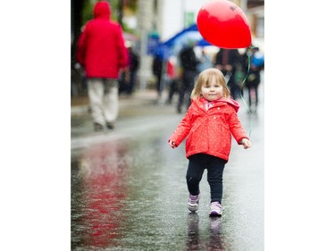 One-and-a-half-year-old Jocelyn Kumpula holds her bright red ballon that matched her rain coat, perfect for the drizzly Saturday morning weather.