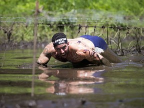 Adam Baccin crawls through the mud and under the barbed wire during the Spartan Sprint Race at Edelweiss Valley Saturday June 18, 2016.