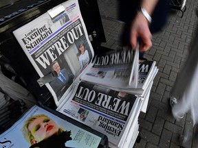 A man takes a copy of the London Evening Standard newspaper with the front page reporting the resignation of British Prime Minister David Cameron and the vote to leave the EU in a referendum.