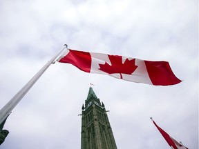 A Canadian flag flies in front of the peace tower on Parliament Hill.