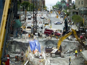 Construction crews were at work Sunday June 12, 2016 as pedestrians and shoppers got a peek of the status of the sinkhole from the pedestrian bridge.