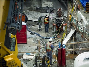 Construction crews were at work Sunday June 12, 2016 as pedestrians and shoppers got a peek of the status of the sinkhole from the pedestrian bridge.   Ashley Fraser