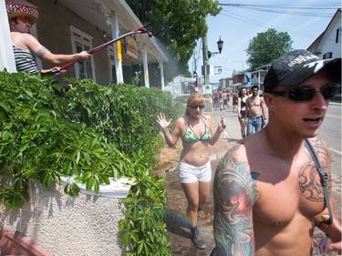 Festival goers take advantage of a man on his balcony offering a cool spray of water as the annual Amnesia Rockfest invades the village of Montebello in Quebec, about an hour away from Ottawa and Montreal.