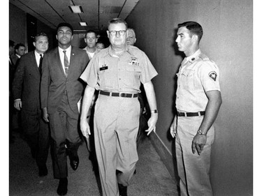 FILE - In this April 28, 1967 file photo, heavyweight boxing champion Muhammad Ali is escorted from the Armed Forces Examining and Entrance Station in Houston by Lt. Col. J. Edwin McKee, commandant of the station, after Ali refused Army induction. Ali, the magnificent heavyweight champion whose fast fists and irrepressible personality transcended sports and captivated the world, has died according to a statement released by his family Friday, June 3, 2016. He was 74.