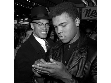 FILE - In this March 1, 1964, file photo, world heavyweight boxing champion, Muhammad Ali, right, is shown with Black Muslim Leader, Malcolm X, outside the Trans-Lux Newsreel Theater  in New York City, after watching a screening of films on Ali's title fight with Sonny Liston in Miami Beach. Ali, the magnificent heavyweight champion whose fast fists and irrepressible personality transcended sports and captivated the world, has died according to a statement released by his family Friday, June 3, 2016. He was 74.