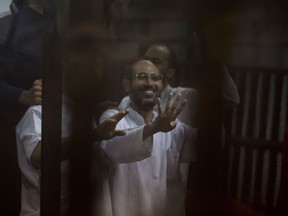 Former employees of the Egyptian presidency under ousted Islamist president Mohammed Morsi give the four-fingered symbol of Rabaah that refers to the deadly dispersal of Morsi supporters in August 2013, inside a defendants cage in a makeshift courtroom at the national police academy, in an eastern suburb of Cairo, Egypt, Saturday, June 18, 2016. An Egyptian court has sentenced six people, including two Al-Jazeera employees, to death for allegedly passing documents related to national security to Qatar and the Doha-based TV network during the rule of Morsi. The former president, the case's top defendant, was also sentenced on Saturday to 25 years in prison. He was ousted by the military in July 2013, and has already been sentenced to death in other cases.