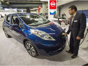 Sales representative Fred Wang plugs in a Nissan Leaf electric car at the Electric Vehicle Symposium, Monday, June 20, 2016 in Montreal.
