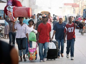 PORT-AU-PRINCE, HAITI - JANUARY 21: People carry their belongings after being displaced when the massive earthquake ravaged the city on January 21, 2010 in Port-au-Prince, Haiti. Planeloads of rescuers and relief supplies headed to Haiti as governments and aid agencies launched a massive relief operation after a powerful earthquake that may have killed thousands. Many buildings were reduced to rubble by the 7.0-strong quake on January 12.