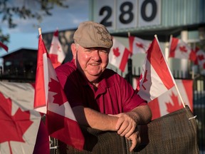 Henry McCambridge stands among several flags he received as gifts after his flags went missing from the front yard of the Fatima Manor in Vanier.