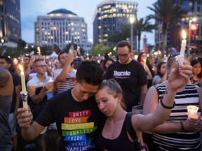 Mourners hold up candles during a vigil for the victims of a mass shooting at the Pulse nightclub in Orlando, Fla.