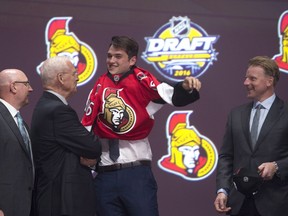 Logan Brown pulls on his sweater as he stands on stage with members of the Ottawa Senators management team at the NHL draft in Buffalo, N.Y. on Friday June 24, 2016.