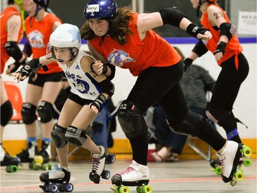 Ottawa Junior Roller Derby's Sharky Dwyer, right, looks to push Montreal Rhythm and Bruise jammer, Évaëlle Piat, left, out of the ring.