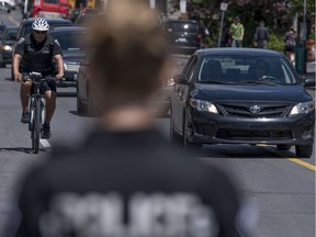 Ottawa Police Service Const. Garth Faubert rides a bicycle equipped with a device that uses sonar to measure how close cars are as they pass him along Somerset St. between Kent St. and Lyon St.