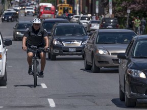 Ottawa Police Service Const. Garth Faubert rides a bicycle equipped with a device that uses sonar to measure how close cars are as they pass him along Somerset St. between Kent St. and Lyon St. in Ottawa Tuesday June 21, 2016.