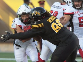 The Ottawa Redblacks' Kienan Lawrence is hit by the Tiger-Cats' Terry Redden during pre-season CFL football action in Hamilton on Friday, June 17, 2016.