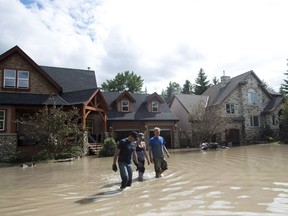 Residents walk through flood waters in Calgary on June 24, 2013. Storms, hurricanes and floods driven in part by climate change will cost the federal disaster fund $902 million a year over the next five years, well above past averages, the parliamentary budget officer predicted Thursday.THE CANADIAN PRESS/Nathan Denette