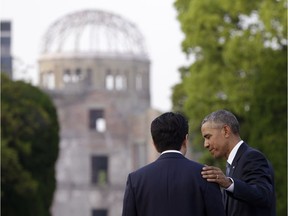 U.S. President Barack Obama, right, and Japanese Prime Minister Shinzo Abe speak with the Atomic Bomb Dome seen at rear at the Hiroshima Peace Memorial Park in Hiroshima, western Japan, Friday, May 27, 2016.
