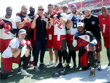 MMA athlete, Misha Cirkunov (centre in sunglasses), poses for pictures with some of the Ottawa Redblacks.