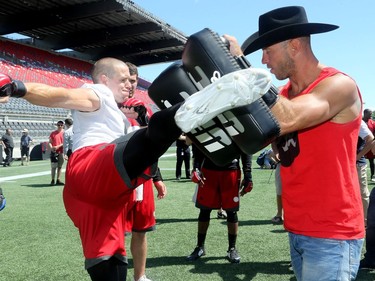 UFC fighter, Donald Cerrone (right) teaches Redblacks wide receiver, Jake Harty, how to throw a good kick.