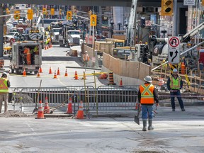 Workers wait for the next plan of action as Ottawa deals with the massive sinkhole on Rideau Street. (Wayne Cuddington/Postmedia)