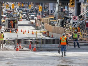 Workers wait for the next plan of action as Ottawa deals with the massive sinkhole on Rideau St which resulted in a number of businesses shutting down.