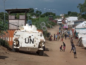 In this photo taken Monday, July 25, 2016, some of the more than 30,000 Nuer civilians sheltering in a United Nations base in South Sudan's capital Juba for fear of targeted killings by government forces walk by an armored vehicle and a watchtower manned by Chinese peacekeepers. South Sudanese government soldiers raped dozens of ethnic Nuer women and girls last week just outside a United Nations camp where they had sought protection from renewed fighting, and at least two died from their injuries, witnesses and civilian leaders said. The rapes in the capital of Juba highlighted two persistent problems in the chaotic country engulfed by civil war: targeted ethnic violence and the reluctance by U.N. peacekeepers to protect civilians. (AP Photo/Jason Patinkin) ORG XMIT: AAS102