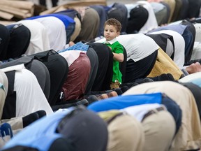 A child plays while the men pray as Ramadan comes to an end and Eid celebrations take place at the EY Centre.  Wayne Cuddington/ Postmedia