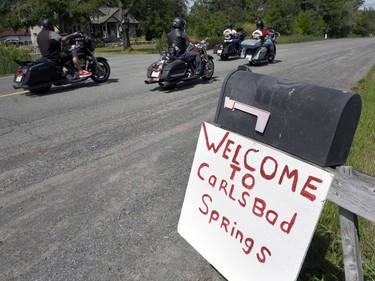 A group of bikers, including members of the Hells Angels from Alberta, ride past a welcome sign posted by neighbours near the Hells Angels Nomads compound during the group's Canada Run event in Carlsbad Springs, Ont., near Ottawa, on Saturday, July 23, 2016.