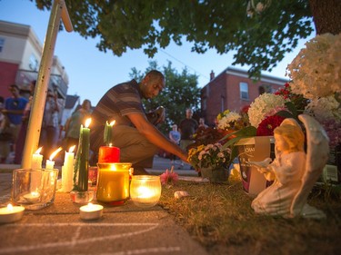 A man looks at the flowers at the front of the apartment building where Abdirahman Abdi lived following the vigil that took place at Somerset Park on Spadina Ave for Abdirahman Abdi, 37, who passed away from injuries he suffered on Sunday during a confrontation with Ottawa Police.   Wayne Cuddington/ Postmedia