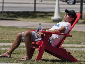 A man reclines in a Muskoka chair in Marion Dewar Plaza, basking in a midday sun.