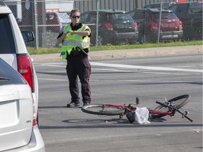 A police officer stands near a bicycle on the ground where a cyclist and car were involved in a collision on West Hunt Club Rd near Costco. The cyclist was taken to hospital.