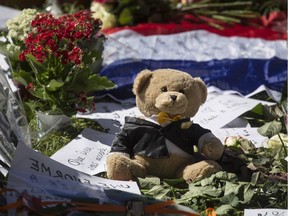 A teddy bear sits with flowers and paper tributes near the scene of a truck attack in Nice, southern France, Saturday, July 16, 2016. The man responsible for turning a night of celebration into one of carnage in the seaside city of Nice was a petty criminal who hadn't been on the radar of French intelligence services before the attack.