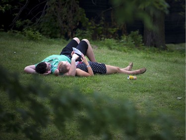 A young couple takes a break in the grass behind the Canadian War Museum at Bluesfest.