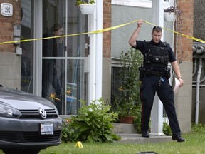 An Ottawa police officer leads non-involved individuals, believed to be residents, from a home inside the crime scene of an overnight homicide in Lowertown in Ottawa on Sunday, July 10, 2016.